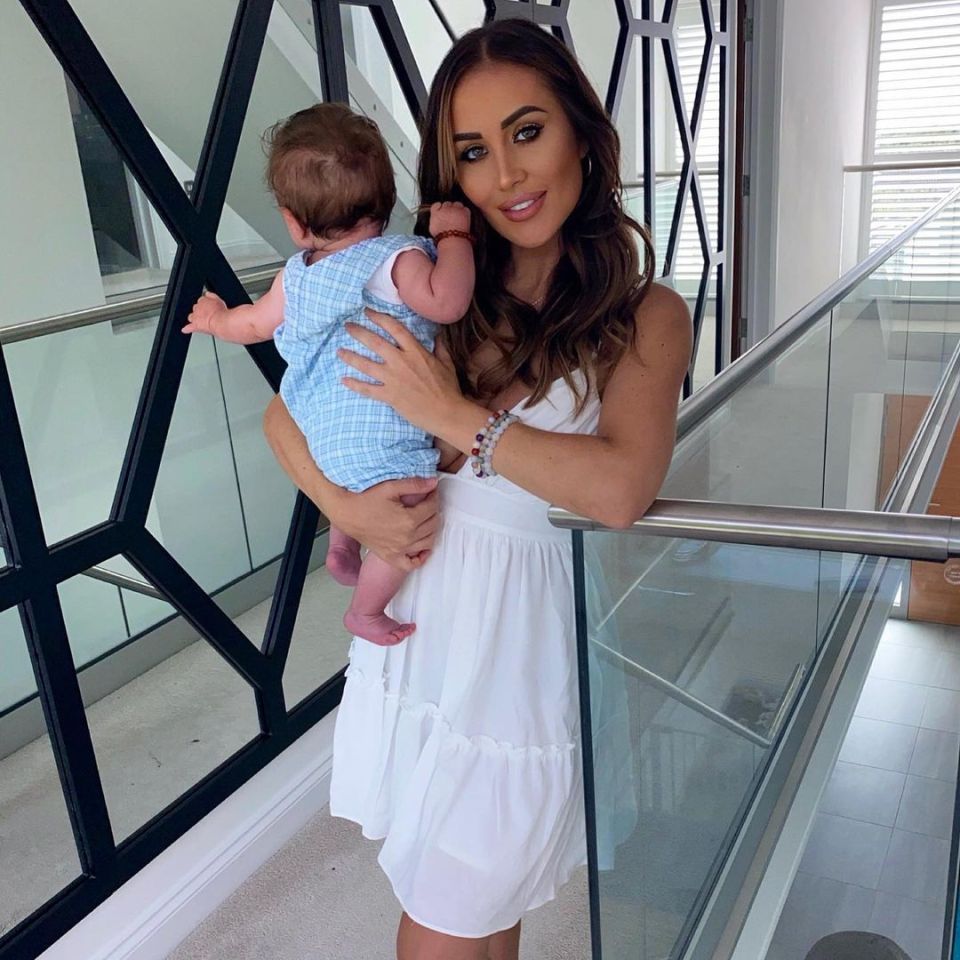 a woman in a white dress is holding a baby