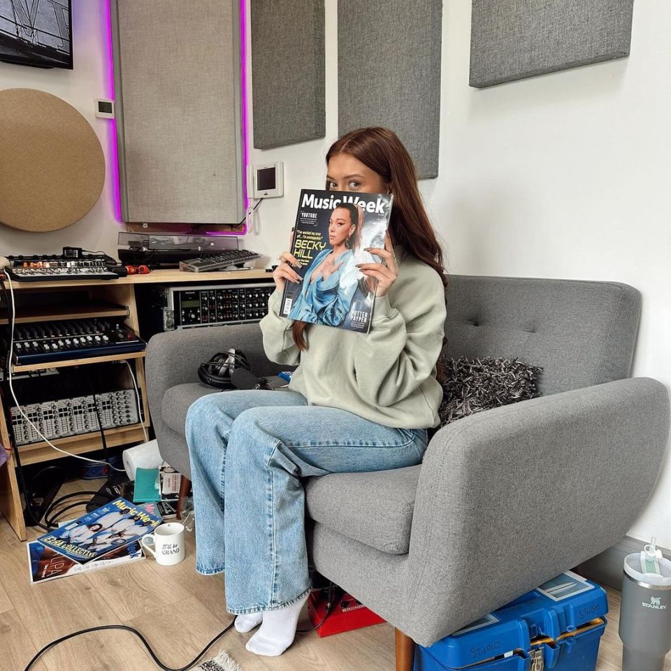 a woman sitting in a chair holding a music week magazine