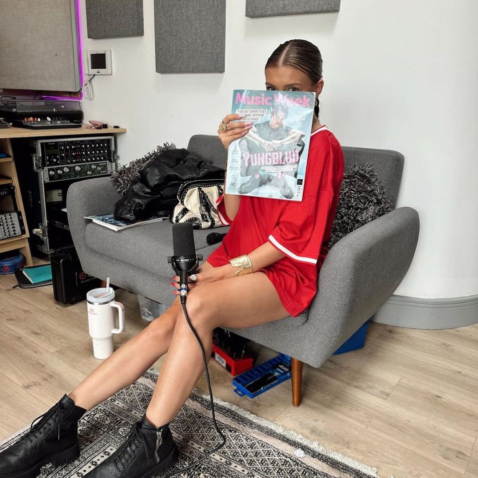 a woman sitting on a couch holding a music week magazine
