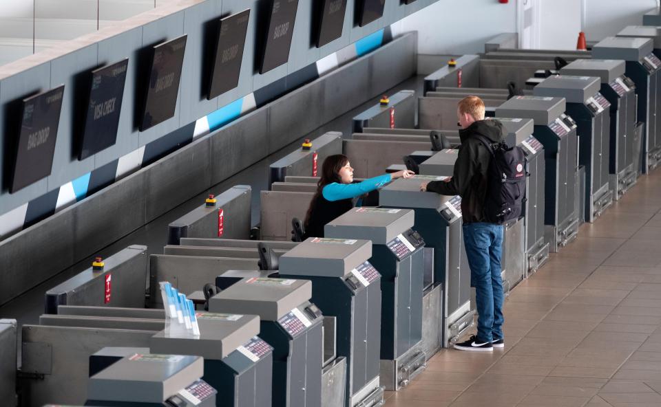 a man and a woman are standing in front of a row of check in kiosks