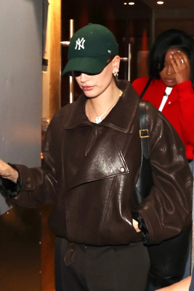 a woman wearing a green ny hat and a brown jacket