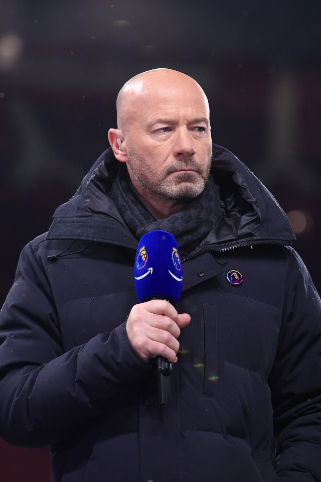 a man in a black jacket is holding a blue microphone with a smile on it