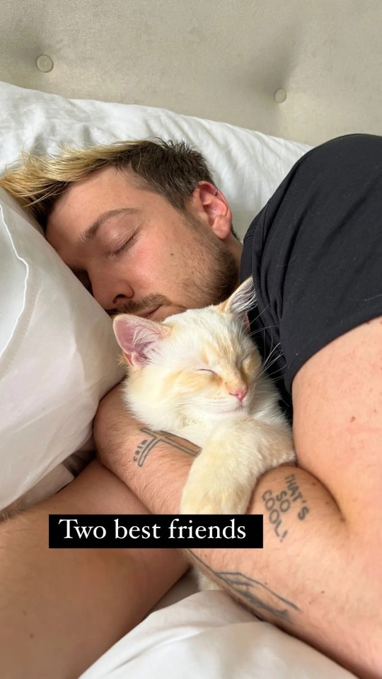 a man with a tattoo on his arm sleeping with a cat