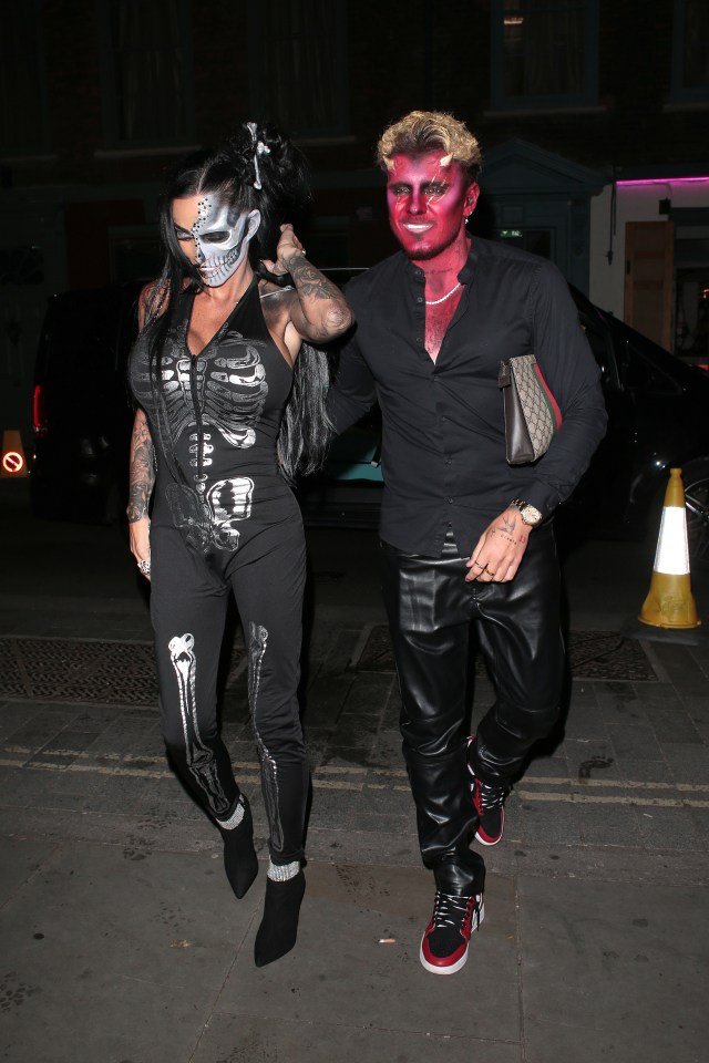 a man with red paint on his face is walking with a woman in a skeleton costume