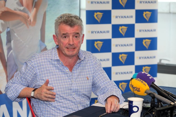 a man sitting in front of a ryanair sign