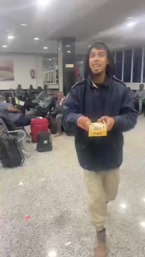 a man is holding a box of food in an airport waiting area .