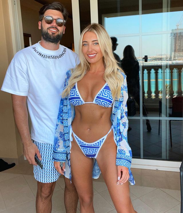 a woman in a blue and white bikini stands next to a man wearing sunglasses