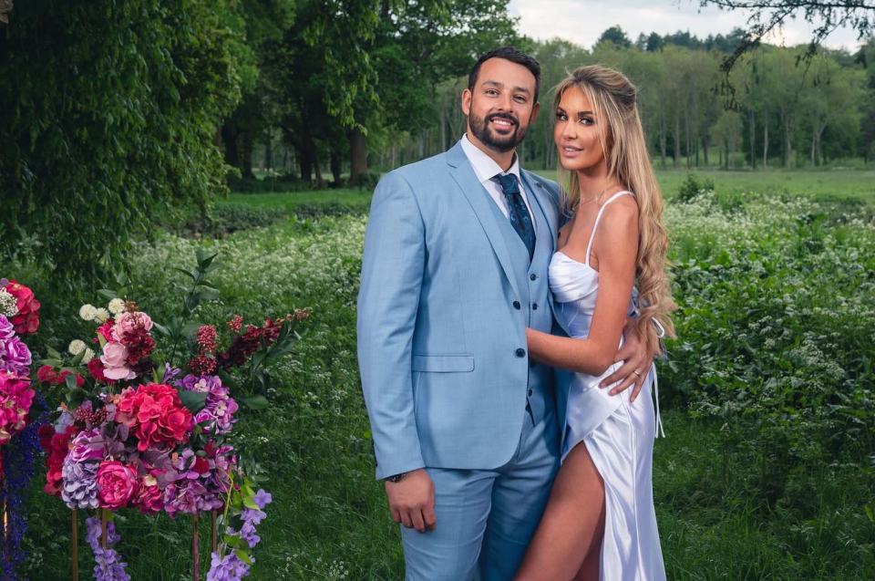 a man in a blue suit stands next to a woman in a white dress