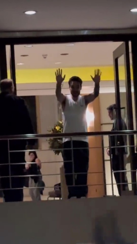 a man standing on a balcony with his hands in the air