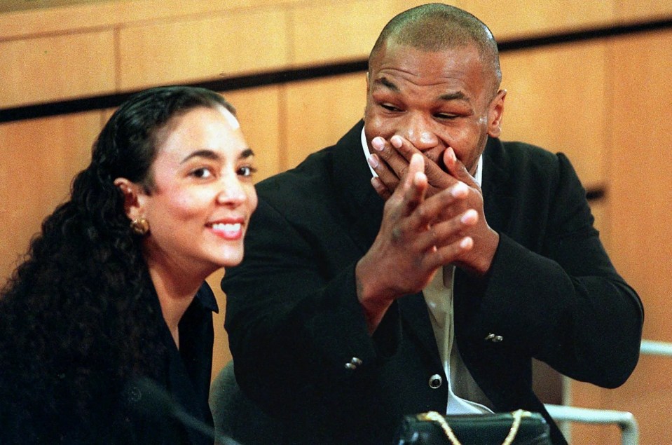 a man covering his mouth with his hands while a woman smiles behind him