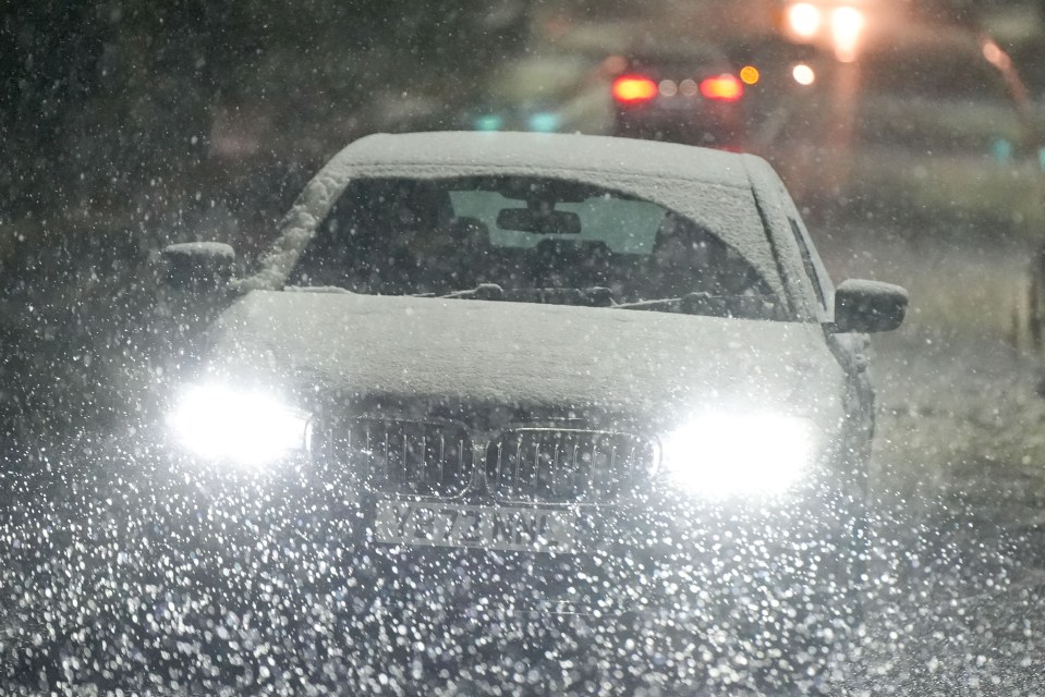 a car with snow on the windshield is driving through the rain