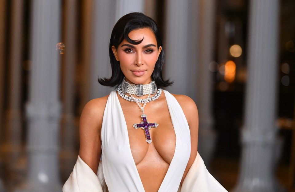 a woman in a white dress has a cross necklace around her neck