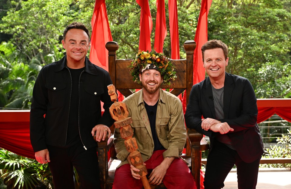 three men are posing for a picture with one wearing a crown