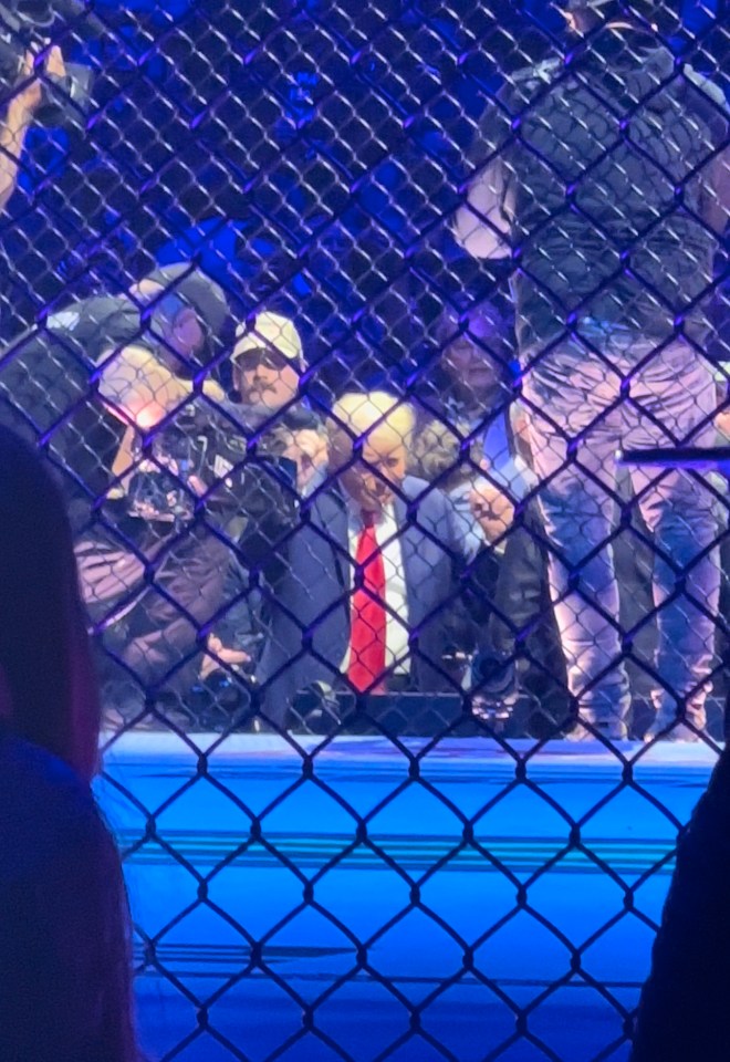 a man in a suit and red tie is behind a chain link fence