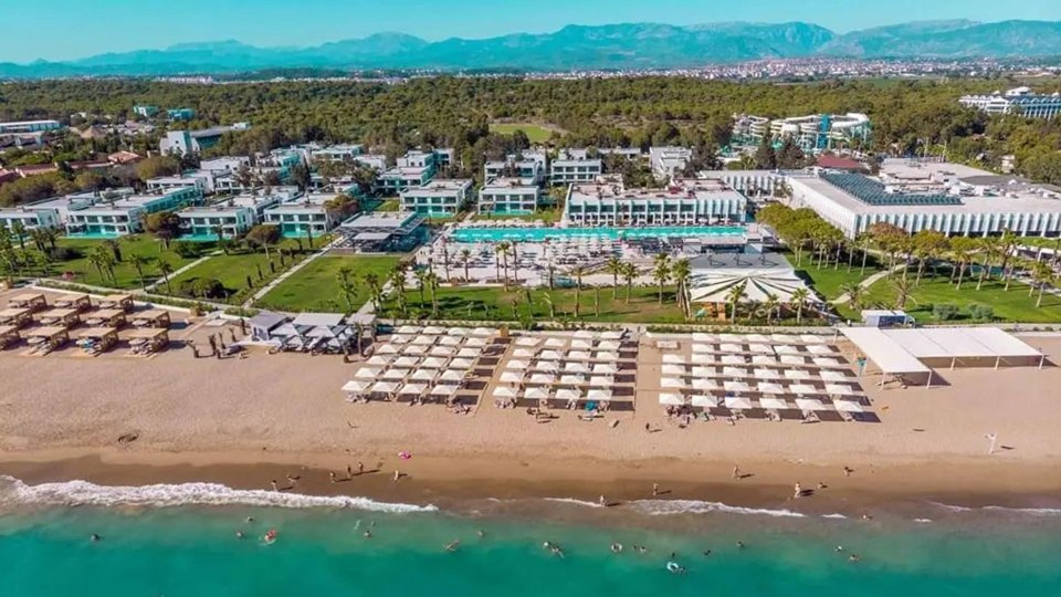 an aerial view of a beach with white umbrellas