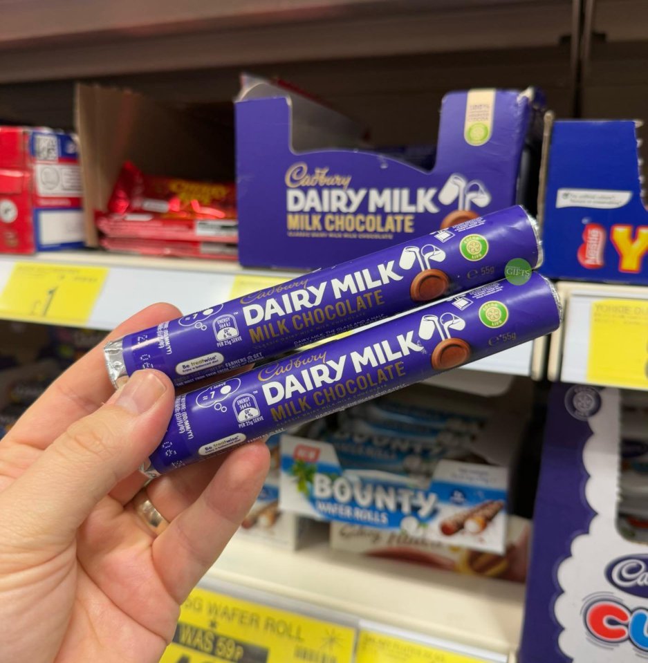 a person is holding two cadbury dairy milk chocolate bars