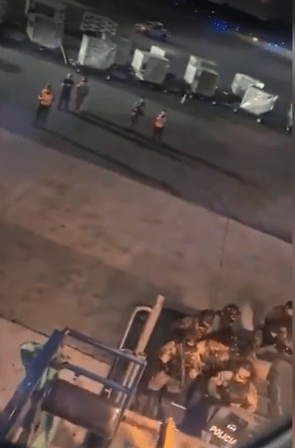 a group of police officers are standing around a forklift at an airport