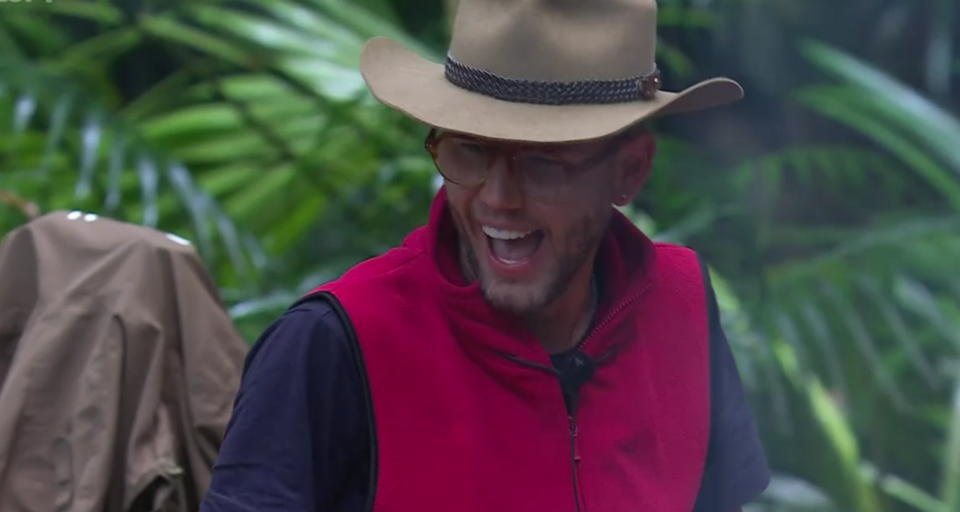 a man wearing a cowboy hat and glasses is smiling
