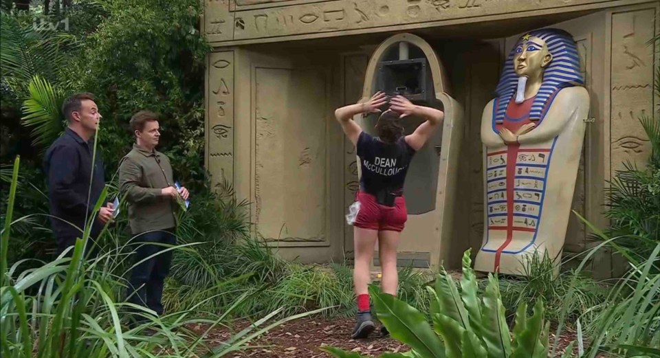a woman in a dean mcdermott shirt stands in front of a statue