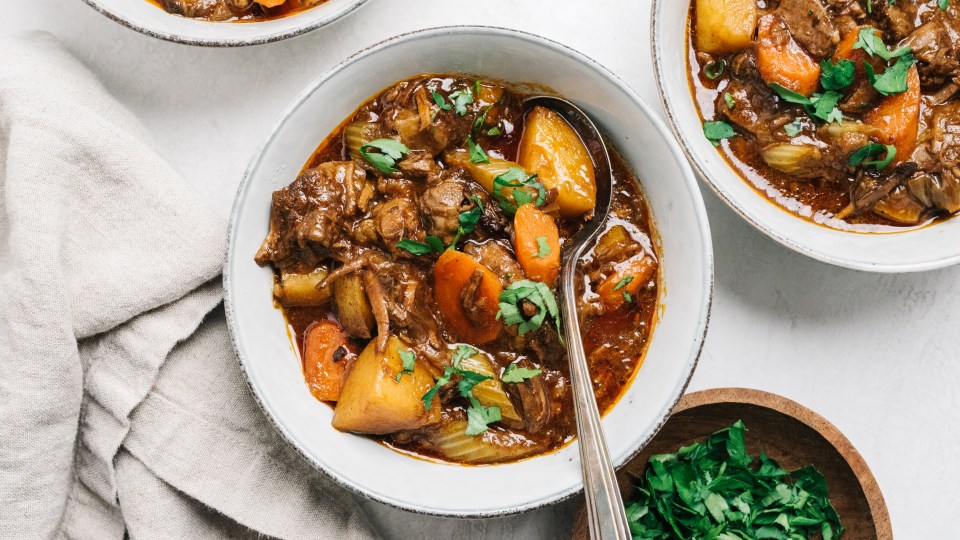 a bowl of stew with carrots and potatoes with a spoon in it