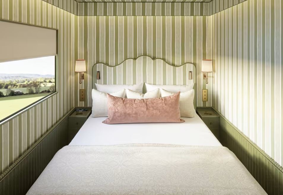 a small bedroom with striped walls and a bed with a pink pillow