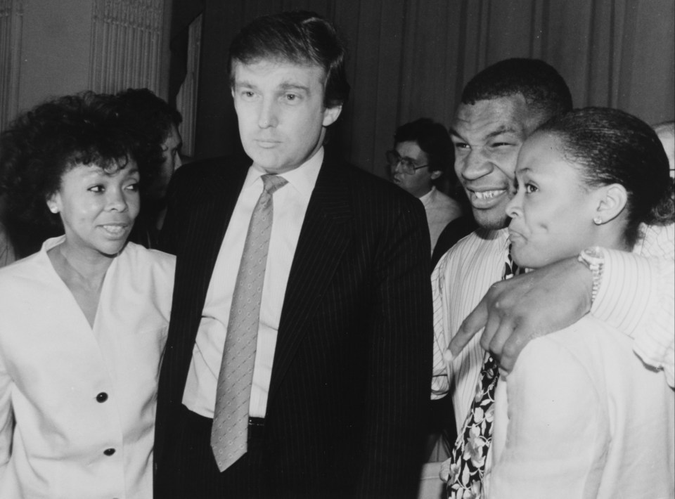 a man in a suit and tie stands next to two women