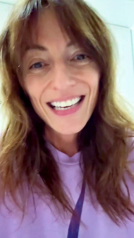 a woman with long hair is smiling and wearing a purple shirt