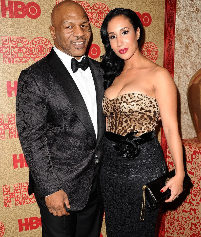mike tyson and his wife are walking on a red carpet