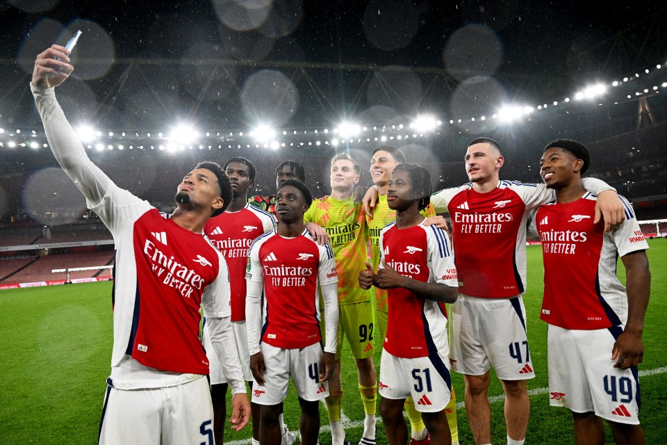 a group of soccer players wearing emirates fly better jerseys pose for a photo