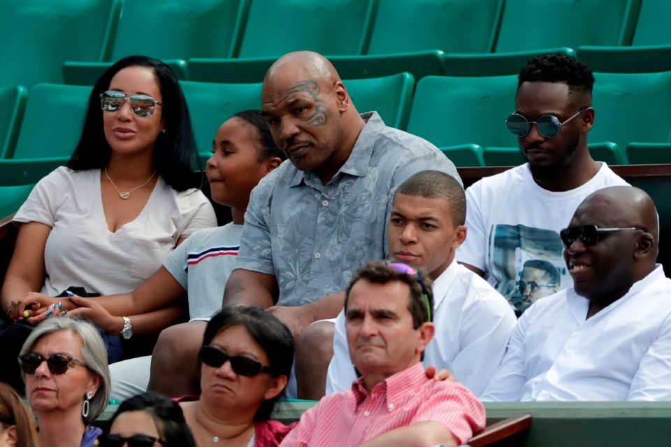 a group of people sitting in a stadium including mike tyson