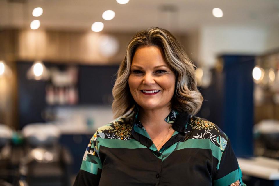 a woman in a green and black shirt smiles for the camera