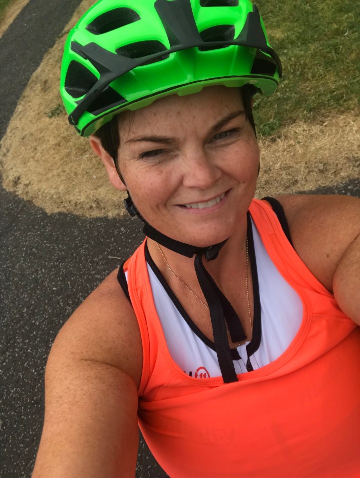 a woman wearing a green helmet and an orange tank top smiles