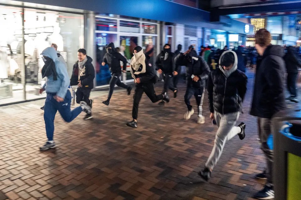 a group of people running in front of a store that says ' adidas ' on it