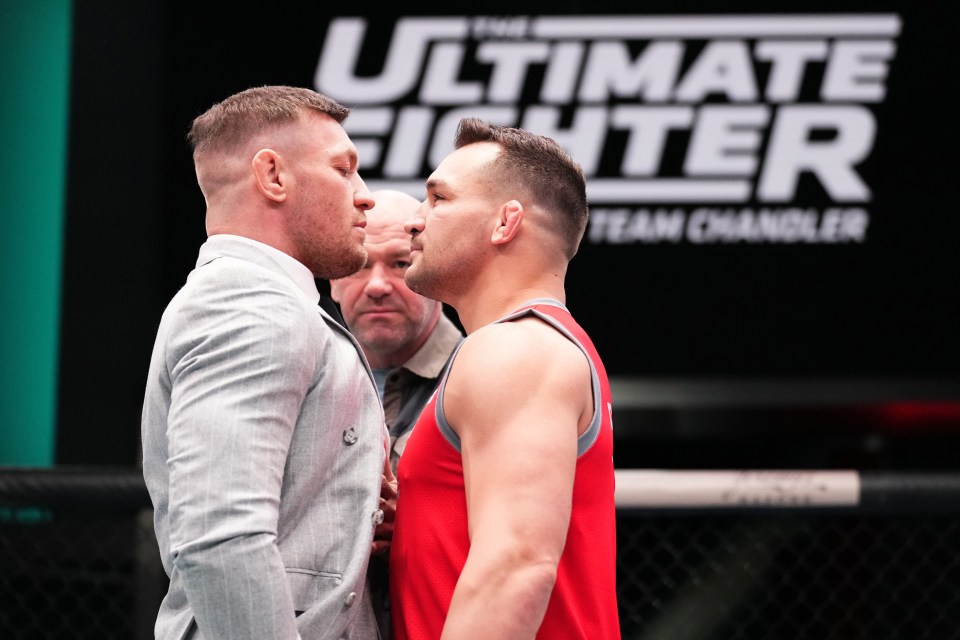two men are facing each other in front of a sign that says ultimate fighter