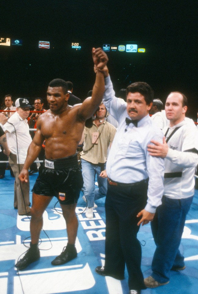 mike tyson is being congratulated by a referee in a boxing ring