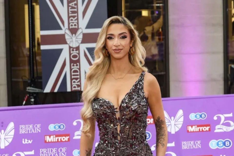 a woman stands on a purple carpet in front of a flag that says pride of britain
