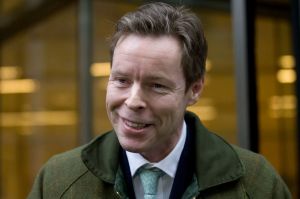 a man in a green jacket and tie smiles for the camera