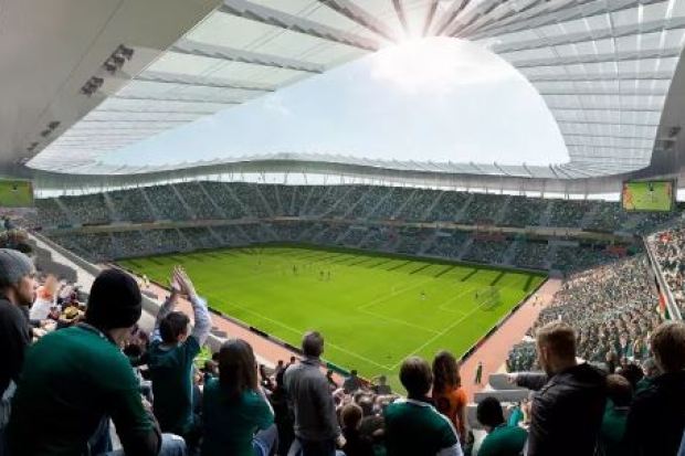 a group of people are sitting in a stadium watching a soccer game .