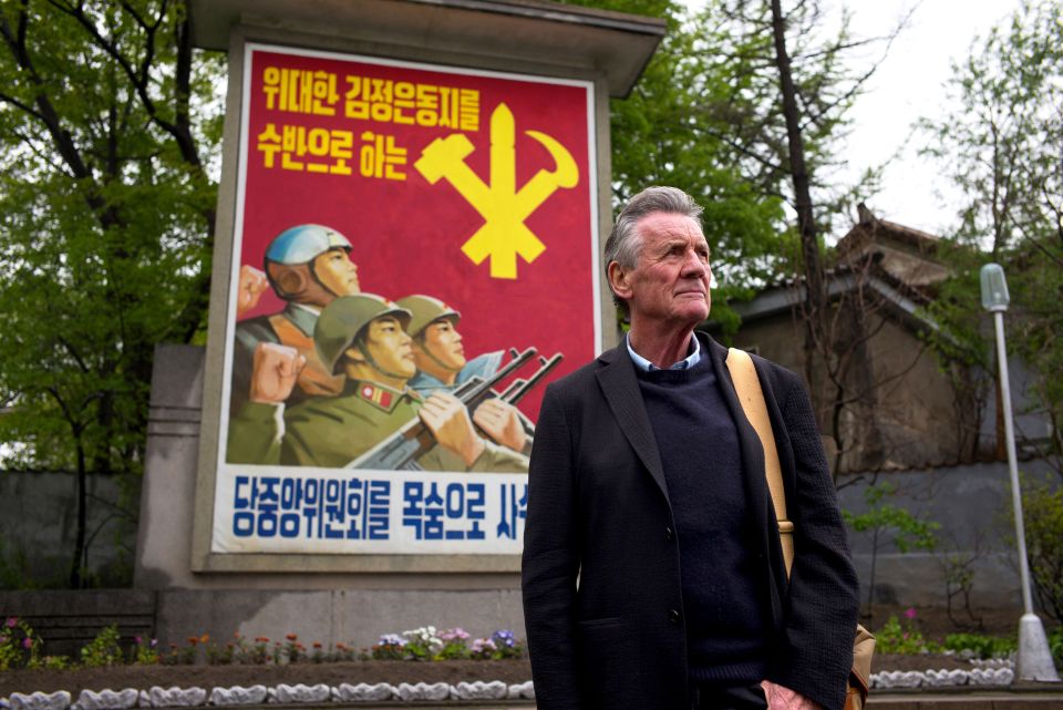 a man stands in front of a poster with soldiers on it