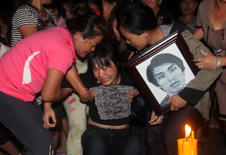 a woman is crying while holding a framed picture of a man
