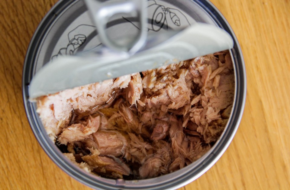 a can of tuna with the lid open on a wooden table