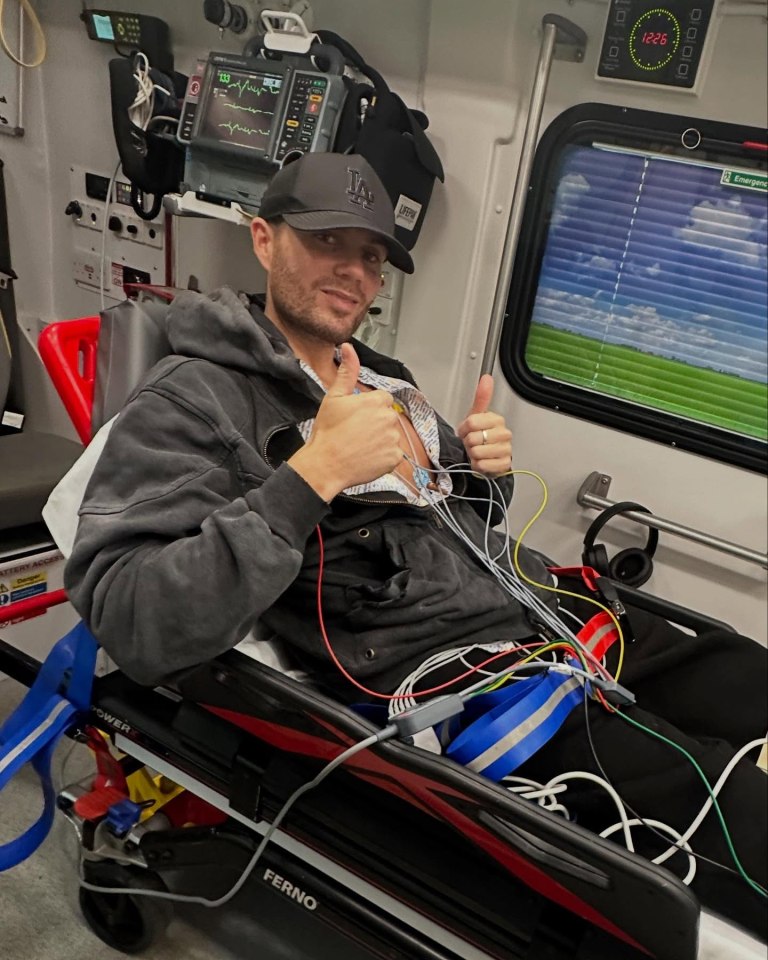 Man in ambulance giving thumbs up during heart scan.