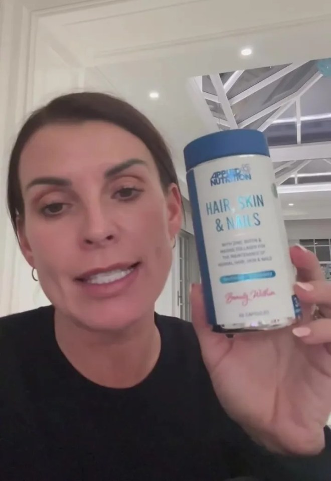 Woman holding a bottle of Applied Nutrition Hair, Skin & Nails supplements.