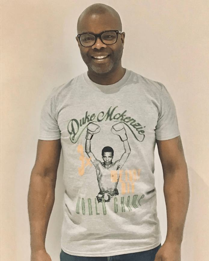 Man wearing a grey t-shirt with a Duke McKenzie boxing graphic.
