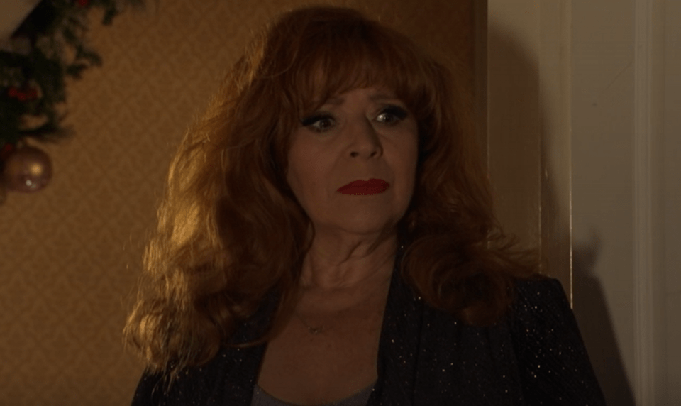 Woman with auburn hair wearing a dark sparkly top.