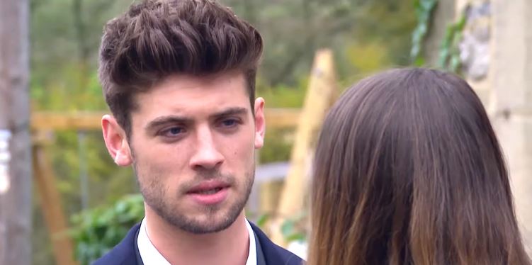 A man with short brown hair looks concerned as a woman's back is turned to him.