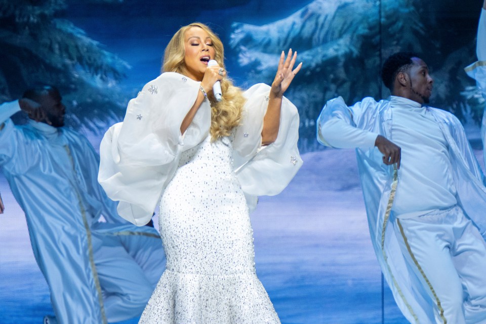 Mariah Carey performing in a white, sequined gown during her Christmas tour.