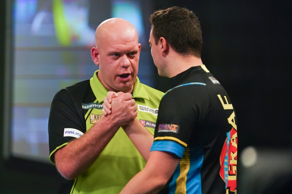 Michael van Gerwen shakes hands with his opponent after winning a darts match.