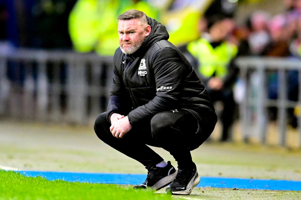 Wayne Rooney, manager of Plymouth Argyle, crouches on the sidelines.
