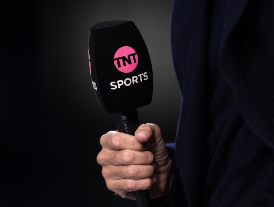 Close-up of a hand holding a microphone with the TNT Sports logo.